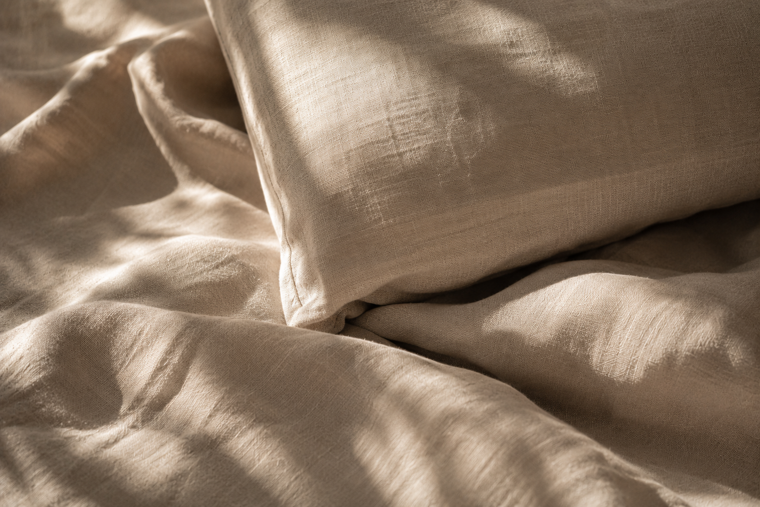 Sun-washed linen bedding in soft Mediterranean light at Aethera House